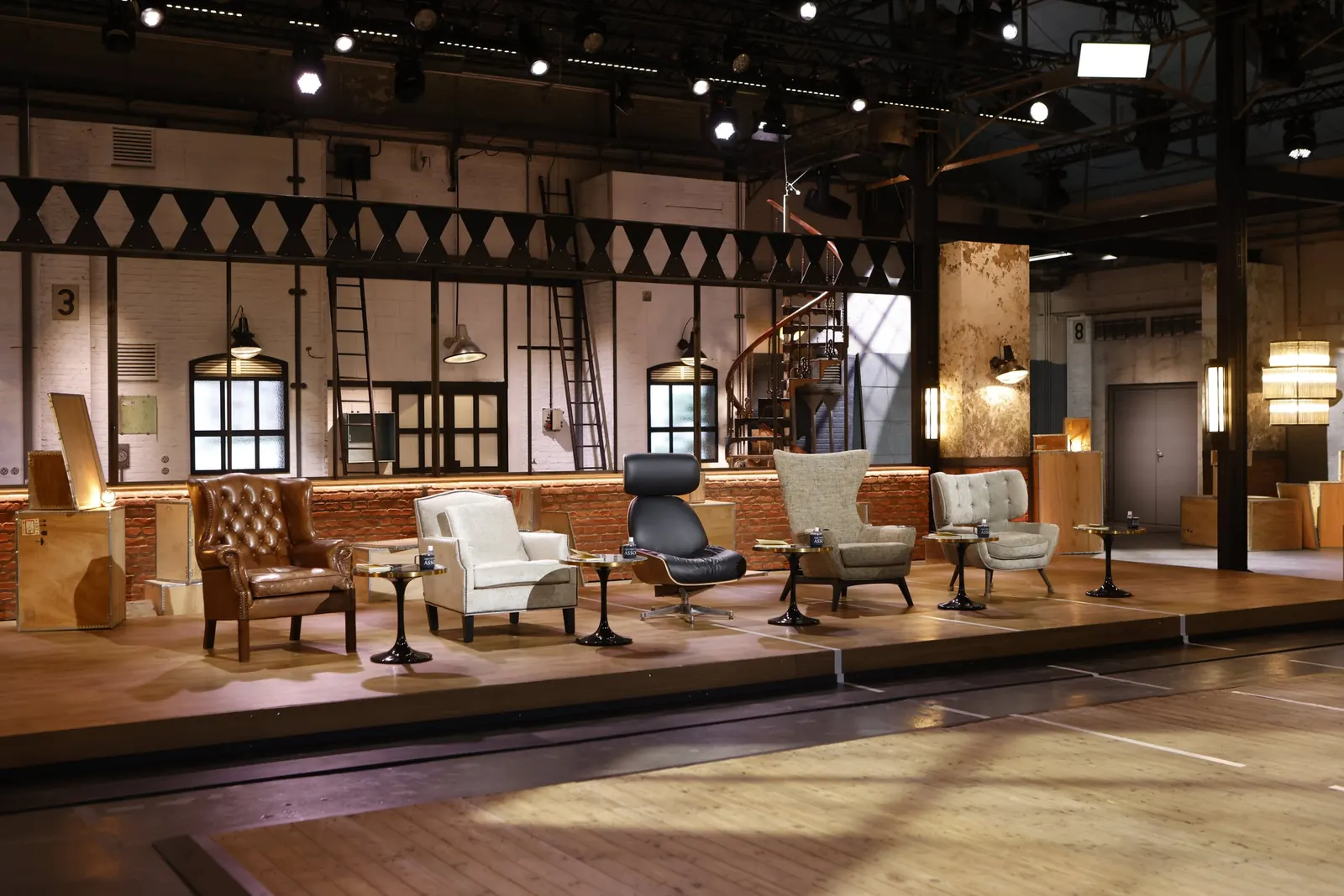 Le plateau de Qui veut être mon associé ? : cinq fauteuils alignés sur une estrade, dans un décor d'atelier industriel